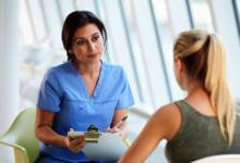 Patient 与 blonde hair meeting 与 female medical practitioner wearing blue scrubs